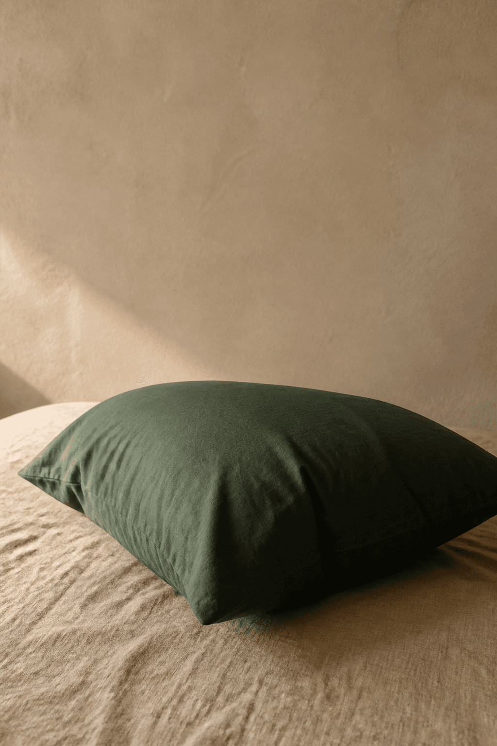 Deep jade green cooling pillowcase on sand-coloured linen