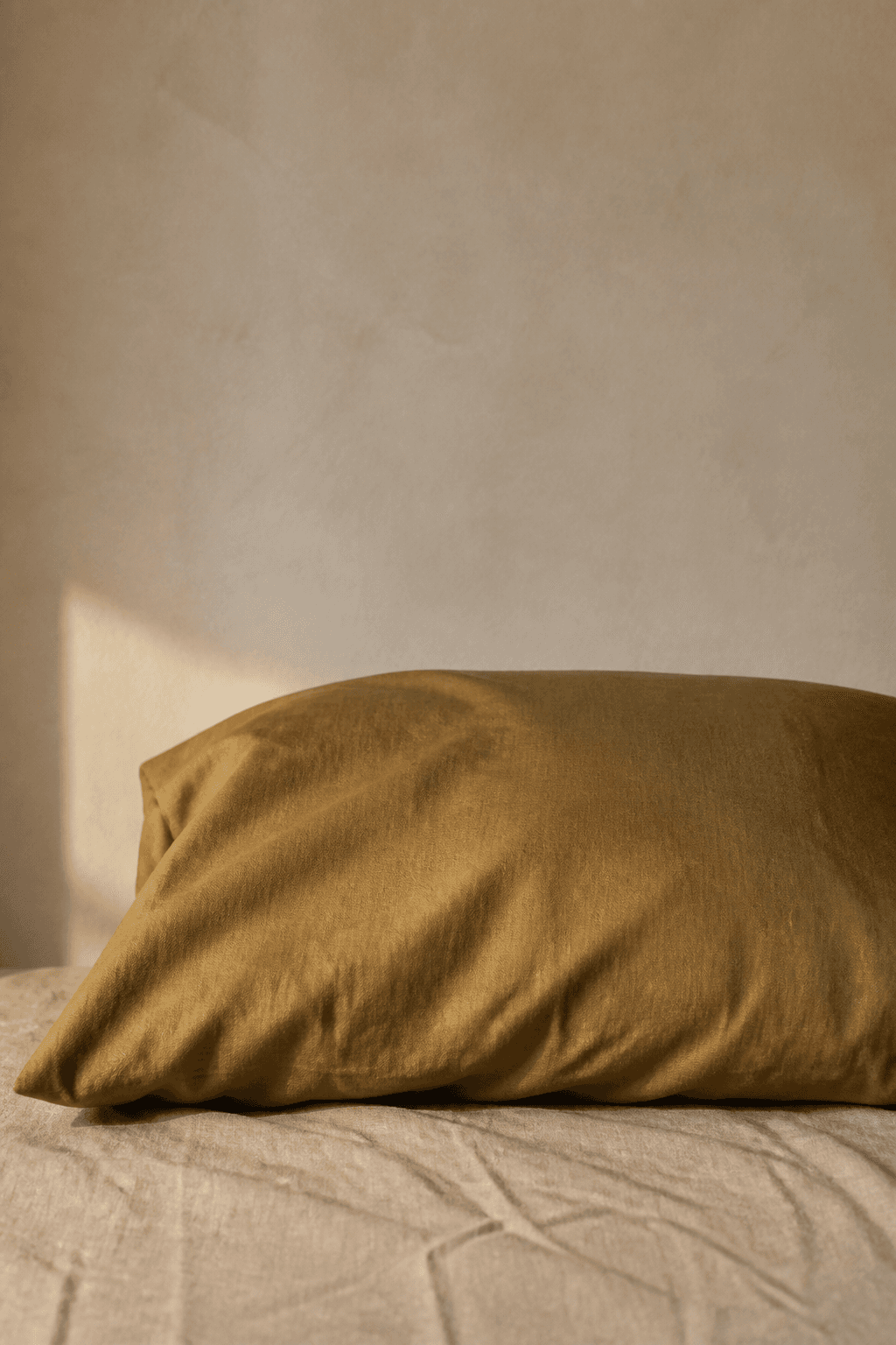 Muted aged-brass silk pillowcase on natural linen